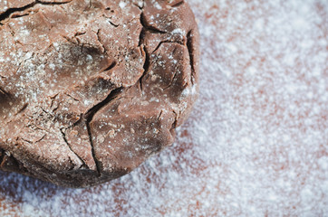 Chocolate dough for cakes on a wooden board, sprinkled with flour