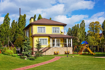 Fototapeta na wymiar Exterior of beautiful house with green yard and children playground