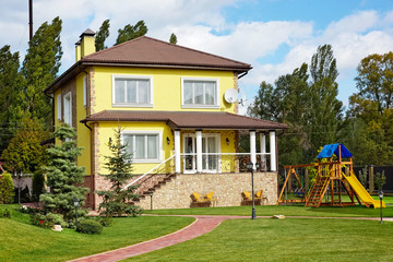 Fototapeta na wymiar Luxury house with green yard, children playground and garden