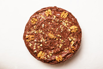 Homemade chocolate cake with nuts, white background, top view