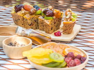 A loaf of fruit cake in wooden plate with defocused of dried fruit, spices and honey