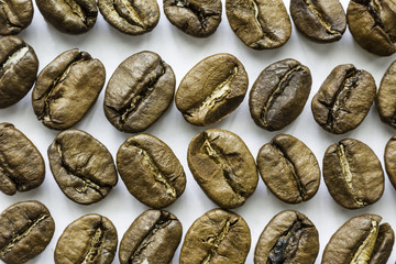 Different directions rows of coffee beans. Different shapes and different shades of brown. White background.Site about food, drinks, health, business.