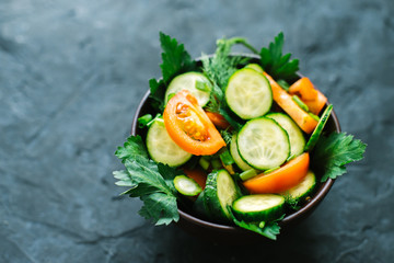 Fresh salad with vegetables on a black matte background. The concept of a healthy diet
