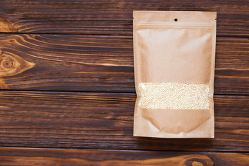 Mockup paper bag with quinoa seeds on white wooden table. Concept of a healthy diet. Super food.
