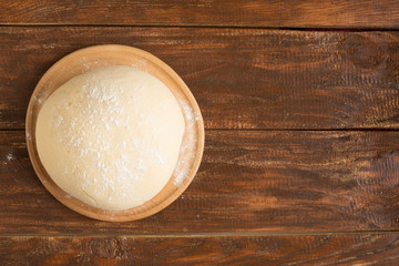 dough for making buns or pies on a wooden background