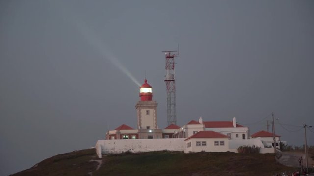 Shinning old lighthouse above pine forest before sunset.