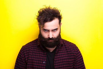 Sad bearded hipster man on yellow background