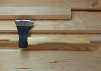 Big sharp ax with black blade and light yellow handle on fresh wooden boards. Wood chopping, construction background with equipment.