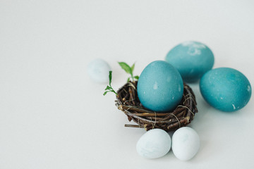 Blue and white painted easter eggs in a nest on a white background. The concept of Easter. Close-up.