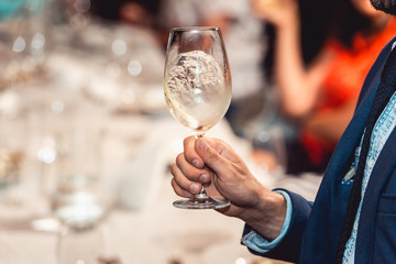man holds glass of red wine. people consider the color of the wine and try how it smells in different glasses