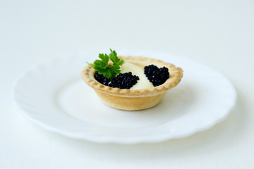 tartlet with caviar and herb on a white plate
