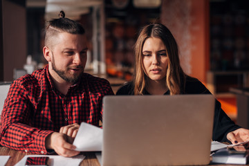 young freelancers man and woman sitting in a cafe and working for a laptop