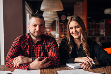 two happy freelancer smiling at camera in cafe