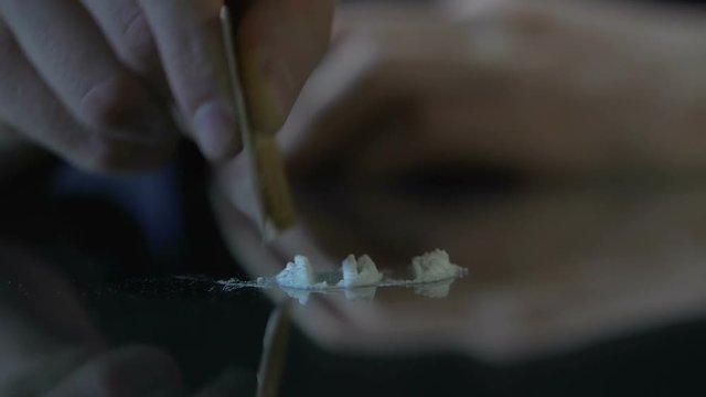 Male hands dividing cocaine lines on glass surface, unhealthy dependence, junky