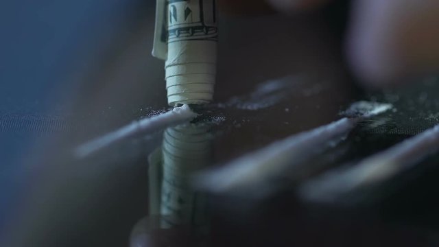 Drug addict sniffing cocaine through rolled banknote, overdose, depression