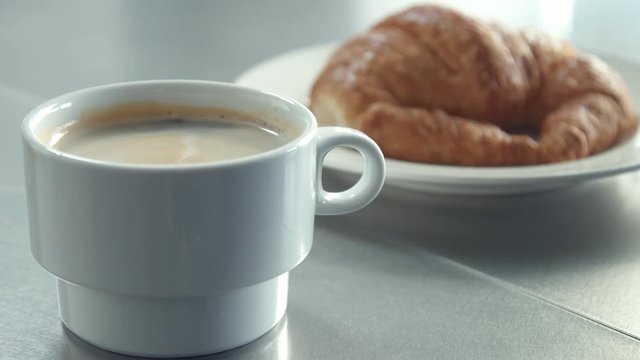 breakfast with coffe and croisant Short clip of tree clips how man's hand put on table dish with croissant and cup of coffe