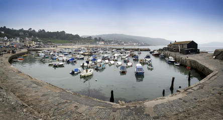 Fototapeta na wymiar Stunning panorama landscape of traditional fishing harbour at Lyme Regis in England