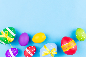 Colorful easter eggs on pastel blue background flat lay. Copy space