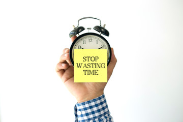 Hand Holding Alarm Clock and Pointing STOP WASTING TIME