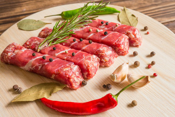 Raw meat. Balkan cuisine. Chevapchichi on a wooden background