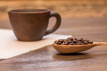   cup of coffee and grain of coffee in a wooden spoon, a useful and tasty drink
