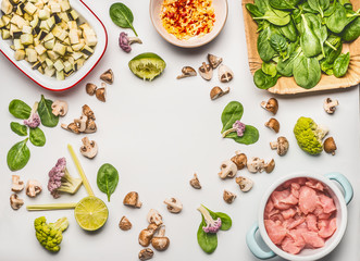 Healthy dieting food flat lay made with spinach, chicken meat , chopped champignons and eggplant, lemon and vegetables on cutting board with cooking spoon on white background, top view, frame