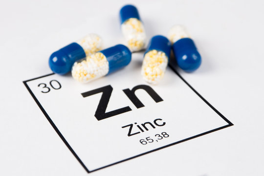 Blue pills with mineral Zn (Zincum) on a white background with an inscription from the chemical table