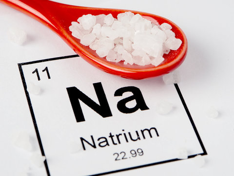 Spoon with salt on a white background with an inscription from the chemical table.