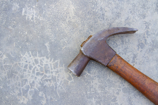 Old nail hammer against cemented background.
