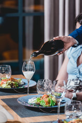 sommelier pouring champagne into glass at wine tasting