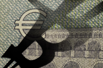 A closeup photo of  a five euro bill with the shadow of the bitcoin symbol falling from the side