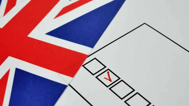 Hand voting in paper ballot by red pencil in United Kingdom with Great Britain flag