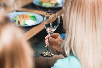 woman holds glass of red wine. people consider the color of the wine and try how it smells in different glasses