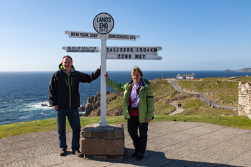 Touristen Frau und Mann mit Wegweiser von Lands End nach Salzburg in Cornwall