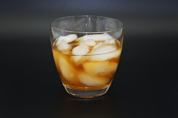 Alkoholisches Getränk mit Eiswürfel im Glas freigestellt auf schwarzem Hintergrund