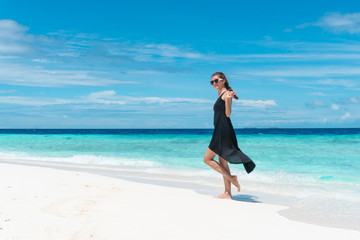 Woman walking on beach with transparent water of ocean in Maldives