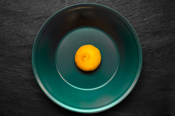Half of Lemon in Deep Green Color Plate Which Placed on Black Stone Surface
