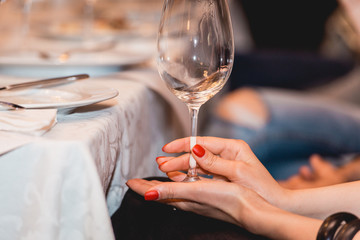 woman holds glass of red wine. people consider the color of the wine and try how it smells in different glasses