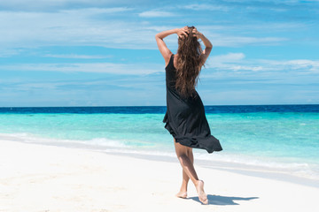 Woman walking on beach with transparent water of ocean in Maldives