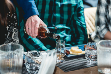 sommelier pouring whiskey into glass at hard alcohol tasting