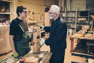 Two master carpenters working together in their woodwork or workshop.