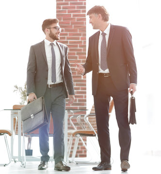 Two businessmen walking along in modern office building