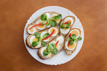 Whole grain sandwiches decorated with chopped egg, red pepper and lettuce salad.