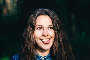 Fine art Portrait of a beautiful curly girl in a summer forest. shows the language. crooked