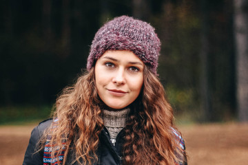  portrait of a cute curly girl in a purple hat in the forest.