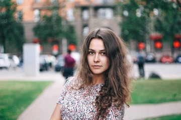 Fototapeta premium portrait of a charming curly-haired girl on a walk in the city.