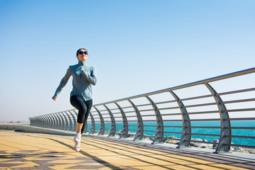 Girl jogging on the boardwalk by the sea