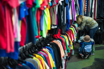Fototapeta na wymiar Woman and child browsing through clothing in a thrift store