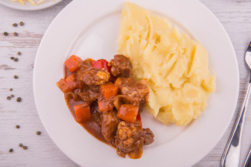Meat ragout with mashed potatoes, is served with vegetables