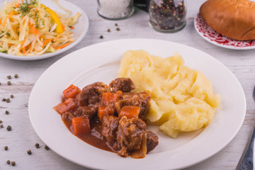 Ragout from meat and vegetables, is served with mashed potatoes potatoes, vegetable salad and pies